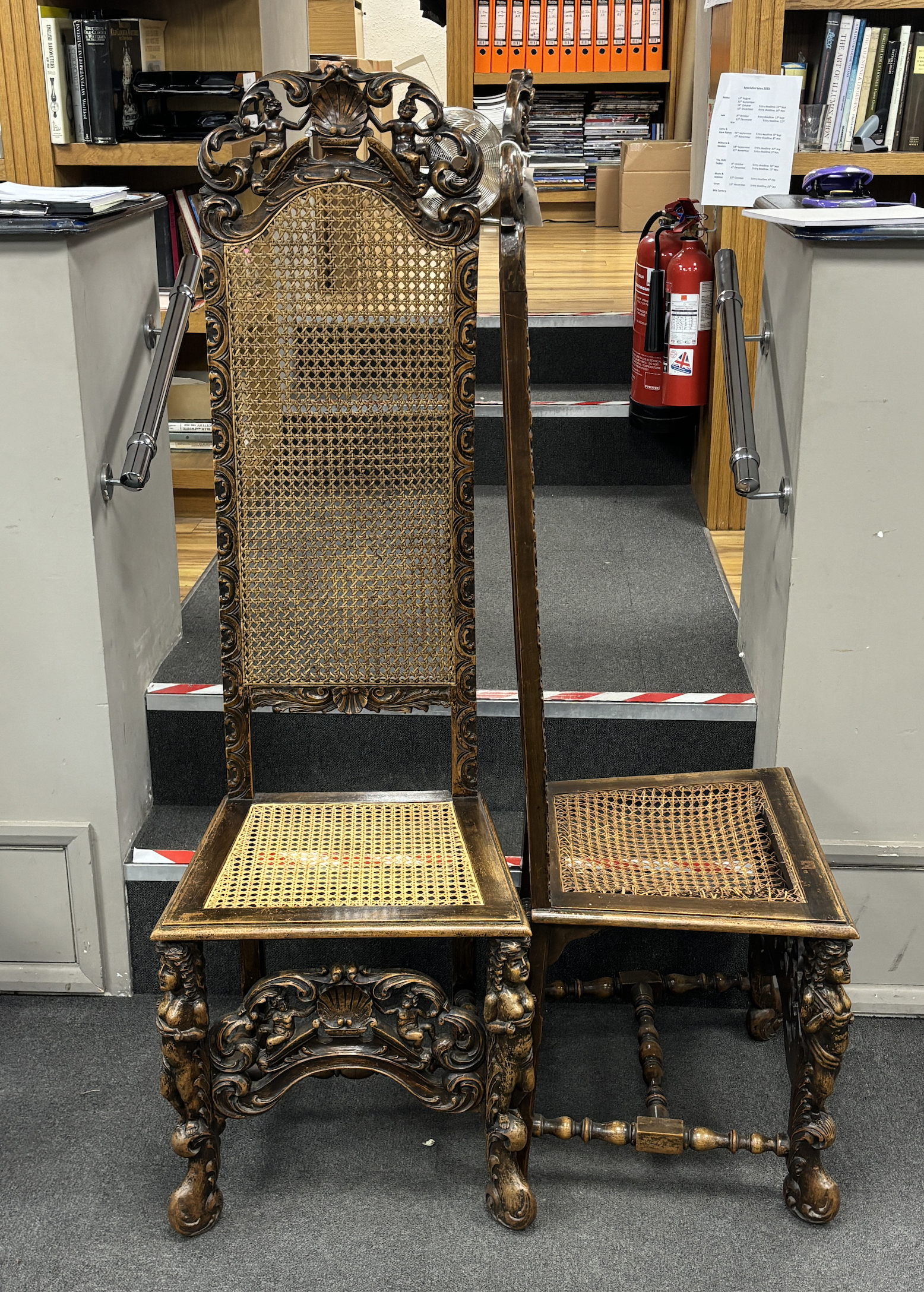 A pair of Cromwellian style carved beech and walnut caned high back hall chairs, height 159cm.